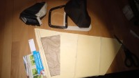 Oben links die Manschette des Wählhebels von Hymer. Daneben das zerpflückte Neuteil und ein Fensterleder, auf dem eine Schablone liegt...